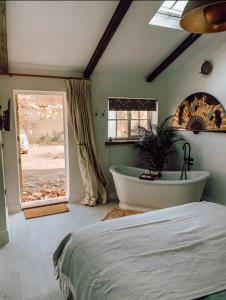 CowdenPriory Cottage Stables的卧室配有床、浴缸和窗户。