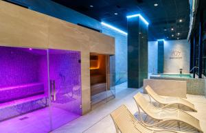 贝尼多姆巴厘大酒店的浴室位于淋浴前,配有紫色照明和椅子