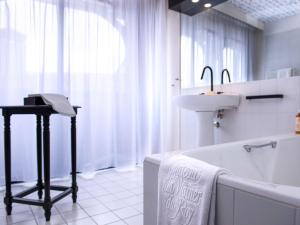 菲雅克Mercure Figeac Viguier du Roy的白色的浴室设有水槽、浴缸和水槽。