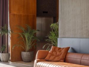 普里什蒂纳Mercure Prishtina City的棕色沙发,位于种有盆栽植物的房间