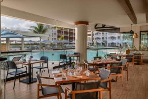坎昆Hilton Cancun Mar Caribe All-Inclusive Resort的一间带游泳池和桌椅的餐厅