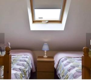 埃文河畔斯特拉特福Surrounded by fields just 3 miles from Stratford - upon Avon - Alveston Pastures Cottage的一间卧室设有两张单人床和一个窗户。