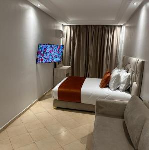 马拉喀什Residence La Perle de l'Atlas Marrakech的一间卧室配有一张床、一台电视和一张沙发