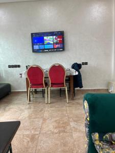 卡萨布兰卡Résidence Faouazi的客厅配有桌子、两把椅子和电视
