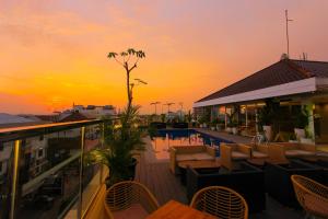 日惹Hotel FortunaGrande Malioboro Yogyakarta的屋顶酒吧,配有桌椅,日落时分