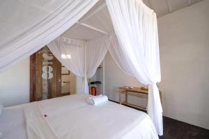 蓝梦岛Paus Putih Hotel的卧室内的白色床和白色窗帘