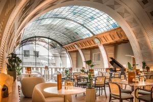 布达佩斯布达佩斯大陆酒店的餐厅设有桌椅和玻璃天花板
