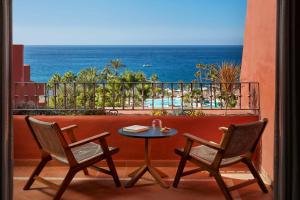 阿德耶Tivoli La Caleta Resort的海景阳台上的桌椅