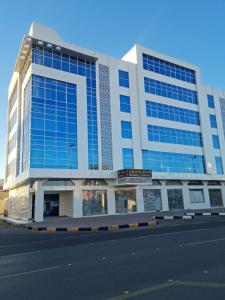 Al Fayşalīyahفندق روزميلون的街道上一座带蓝色窗户的大型建筑