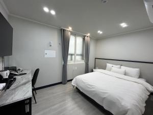 木浦市Hotel Bom的一间卧室配有一张床、一张书桌和一个窗户。
