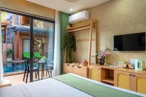 会安The Linh Seaside Villa Hoi An的一间卧室设有一张床、一台电视和一个阳台。