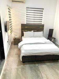 阿布贾CHRIS SPORSHE的一间卧室配有一张带白色床单的大床