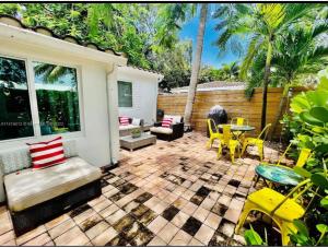 劳德代尔堡Private Fort Lauderdale cottage的庭院设有黄色的椅子和桌椅
