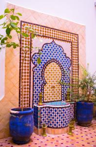 马拉喀什RIAD LAICHI的三只蓝色花瓶坐在一个有神殿的瓷砖地板上