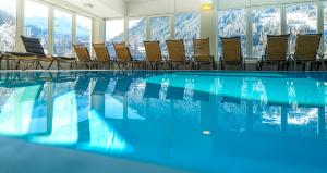 巴德加斯坦Panorama Spa Lodges DAS.SCHILLER的一个带椅子的游泳池,背景是山脉