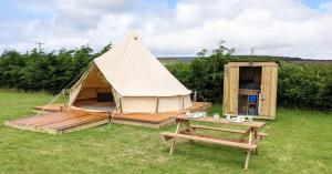 特鲁罗Penhallow Glampsite的帐篷配有野餐桌和长凳