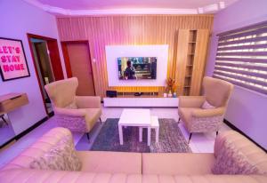 伊凯贾Palm Heights Apartments - Omole Phase 1, Ikeja的客厅配有沙发、椅子和电视