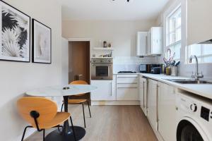 伦敦The Elmington Estate Place - Elegant 1BDR Flat的厨房配有白色橱柜和桌椅