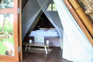 Santa CruzDragon's Garden的一张位于帐篷内的床位,配有一张桌子上的笔记本电脑