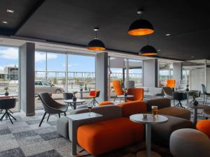 迪耶普迪耶普美居公寓酒店的一间设有橙色椅子和桌子的等候室,窗户