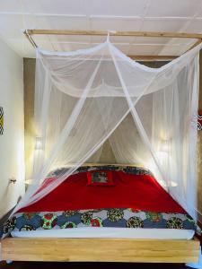 RuhengeriIsange Paradise Resort的一间卧室配有一张红色和白色天蓬床