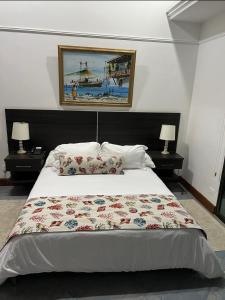 哥伦比亚港Porto Bello Hotel Boutique的一间卧室配有一张带两盏灯的大型白色床。