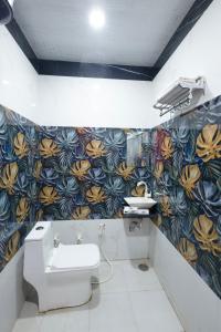 马图拉Hotel Superhouse by Wisdom Madhav的一间带卫生间和花卉图案墙壁的浴室