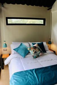 拉维加Luxury Glamping - Tiny House al natural的一间卧室配有白色床和蓝色枕头