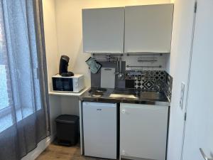 莫伯日superbe studio meublé avec parking的厨房配有白色橱柜、水槽和微波炉