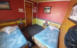 蓬塔阿雷纳斯Hospedaje Independencia y camping的配有红色墙壁的小客房内的两张床