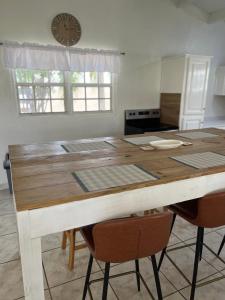 SavanetaLa Villas at Pos Chiquito Caribbean Paradise in Aruba的一张带椅子的厨房桌子和墙上的时钟