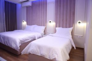 KukësSky View Hotel & Restaurant的紫色照明的酒店客房内的两张床