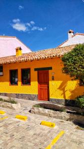 杜伊塔马Casa Mostaza Pueblito Boyacense的停车场里红色门的黄色建筑