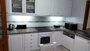 阿威罗Lovely Apartment Aveiro的厨房配有白色橱柜和炉灶烤箱。