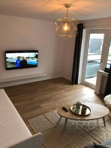 奥伯豪森Sanierte 2 Zimmer Wohnung am CentrO in Oberhausen的客厅配有桌子和墙上的电视
