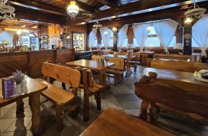 乌斯特龙SCHRONISKO GOŚCINIEC RÓWNICA的一间带木桌椅的餐厅和一间酒吧
