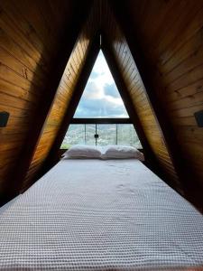 多明戈斯马丁斯Cabana em Domingos Martins的木制客房的一张床位,设有窗户