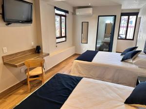 塔斯科·德·阿拉尔孔Centrico House的一间卧室设有两张床,墙上配有电视。