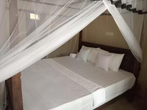 坦加拉Appu Villa的一张带白色床单和枕头的天蓬床