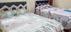 Puerto CallaoPARAISO的一间卧室配有两张带粉色和白色床单的床