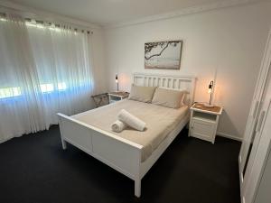 BroadwaterPeppermint Cottage的卧室配有白色的床和2扇窗户。