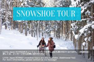 汤泽町Little Japan Echigo的两个人沿着雪覆盖的小径走