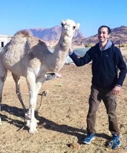 亚喀巴Bedouin experiences的一个人站在骆驼旁边