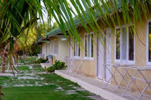 特鲁克巴库Trikora Beach Club and Resort的一座带椅子和棕榈树的建筑