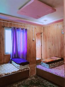 SombāriBODHI VILLA的紫色窗帘间内的两张床