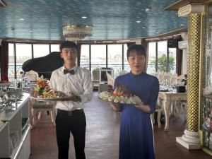 下龙湾Halong AQUAR CRUISE的两人在餐厅里拿着食物盘