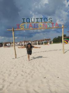 伊基托斯URREAHOUSE IQUITOS的站在标牌前在海滩上行走的人