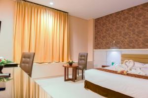 古邦Sahid T-More Hotel的酒店客房带一张床、一张桌子和椅子