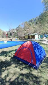 库夫里Chhawani Pro Trek & Camping的坐在草地上的红蓝色帐篷