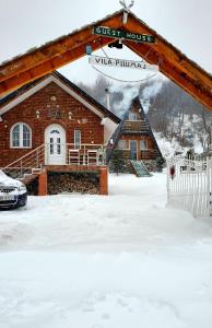 Gropat e SelcësVilat Pllumaj的雪中的房子,有旅馆标志